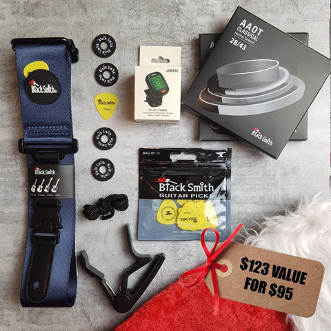 BlackSmith navy blue guitar strap, yellow guitar picks, 3 pack of nylon normal tension strings, Aroma digital chromatic tuner, BlackSmith strap locks, black capo,  and a Christmas stocking on a grey background. Tag says '$123 value for $95" 