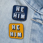 Blue and orange He Him pronoun pin on collar of denim jacket