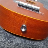 Chrome strap button affixed to base of ukulele