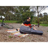 Man playing classical guitar in park with CRDG205CGY Crossrock deluxe metro series gig bag in foreground and bicycle in background