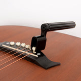 Black peg winder being used to remove pins on a guitar