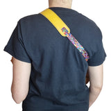 Double hook ukulele strap worn by model shown from rear with brown padded shoulder strap